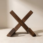 Wooden 'X' block on a beige surface with a neutral background