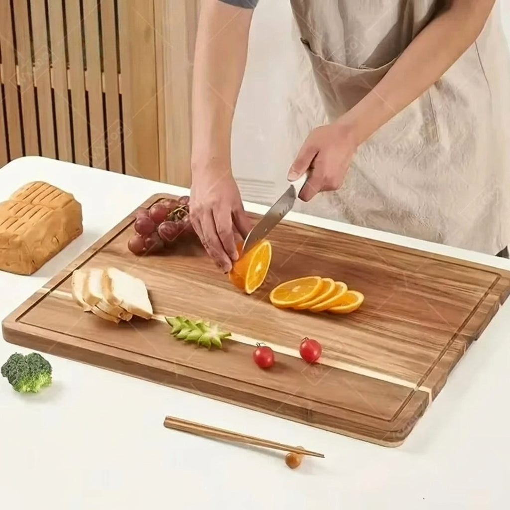 Person slicing oranges on a wooden cutting board with various fruits and vegetables.