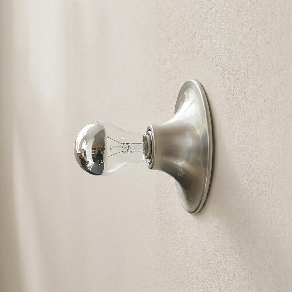 Wall-mounted light fixture with a clear bulb on a beige wall