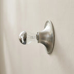 Wall-mounted light fixture with a clear bulb on a beige wall
