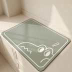 Green mat with a white cartoon design on a light wooden floor.