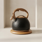 Black kettle with wooden handle and base on a neutral background