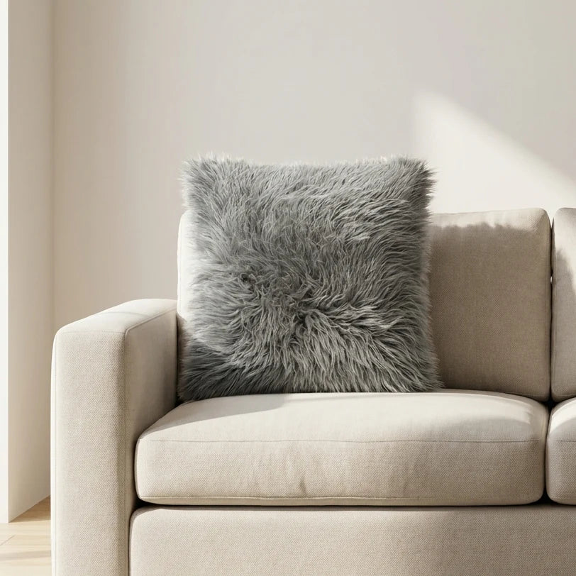 Beige sofa with a fluffy gray pillow in a minimalistic room.