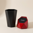 Black geometric vase and red 'PUSH' button on a beige background