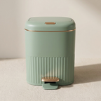 Green trash bin with a step pedal on a beige background