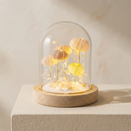 Decorative lamp with jellyfish inside a glass dome on a wooden base against a beige background