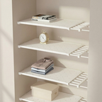 Closet with white shelves containing clothes, a clock, and books.