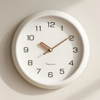 White wall clock with black numbers and brown hands on a beige background