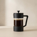Black French press with coffee on a beige background