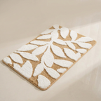 Beige and white leaf-patterned bath mat on a beige background