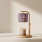 Table lamp with a purple glass shade and a candle on a beige background