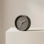 Gray clock with gold hands on a beige surface and background