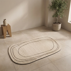 Beige bath mat on a tiled floor with a plant and wooden stool in the background