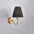 Wall-mounted lamp with black shade and gold arm on a gray background