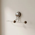 Wall-mounted metal hook with wooden knobs on a beige wall