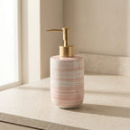 Ceramic soap dispenser with gold pump on a neutral background