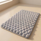 Gray textured bath mat on a beige floor