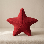 Red knitted star-shaped object on a beige surface