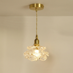 Decorative pendant light with floral glass shade and gold fixture on a beige background