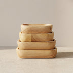 Set of four wooden bowls stacked on a neutral background