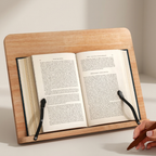 Wooden reading stand holding an open book with a hand holding a pen on a light background