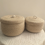 Two woven storage baskets with lids on a textured surface.