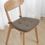 Wooden chair with a gray cushion on a wooden floor.