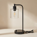 Black table lamp with a clear glass shade on a beige background