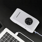 White electronic device with digital display connected to a laptop on a dark surface