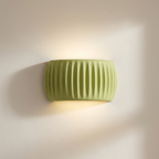 Green wall-mounted light fixture on a beige wall