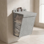 Gray laundry basket with clothes hanging on a wall-mounted holder in a bathroom.