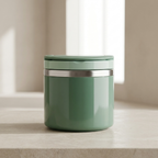 Green cylindrical container with silver lid on a light surface