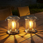 Two illuminated solar lanterns on a wooden surface at night.