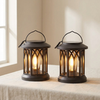 Two lit black lanterns on a table with a neutral background