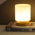 Lamp on a book with a warm glow against a textured wall.