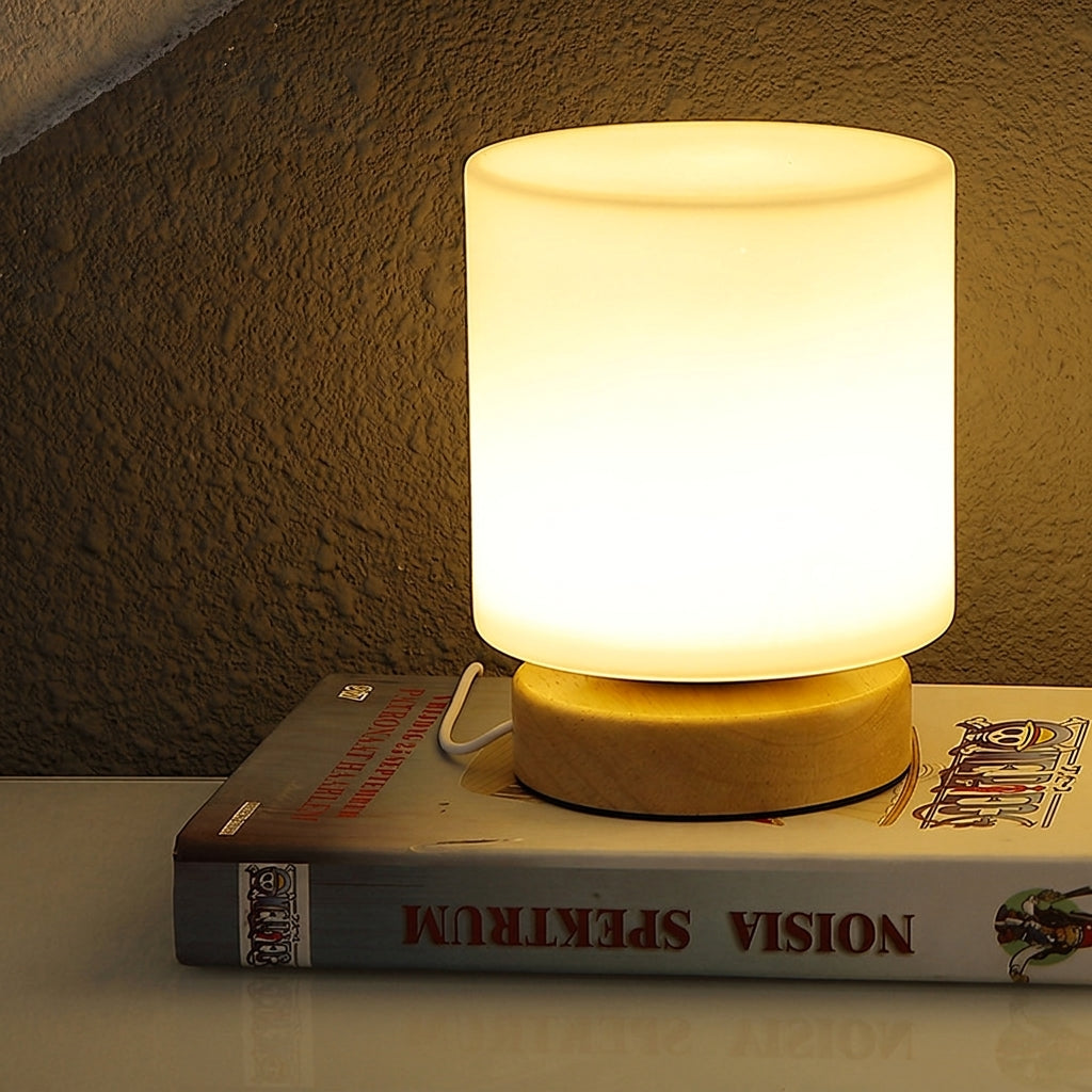 Lamp on a book with a warm glow against a textured wall.