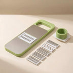Multifunctional kitchen tool with green handle and silver components on a beige background