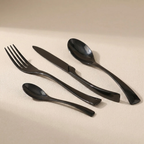 Set of black cutlery including a fork, knife, and two spoons on a beige surface.