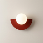 Wall-mounted light fixture with a red half-circle base on a beige wall