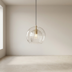 Modern pendant light with clear glass shade and gold fixture in a minimalistic room.