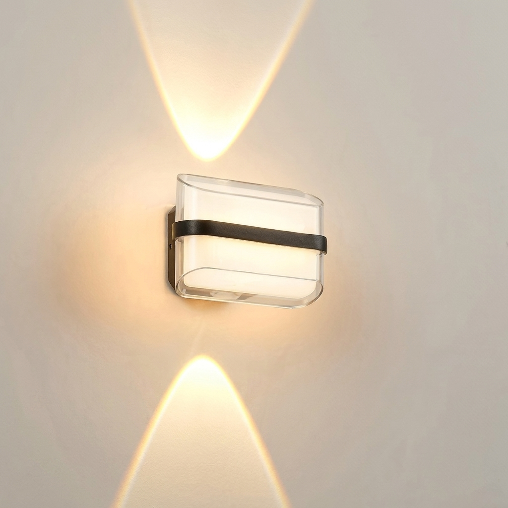 A modern wall-mounted light fixture with a clear rectangular glass shade and a horizontal black band, shown lit against a plain beige wall with warm light beams reflected upward and downward.