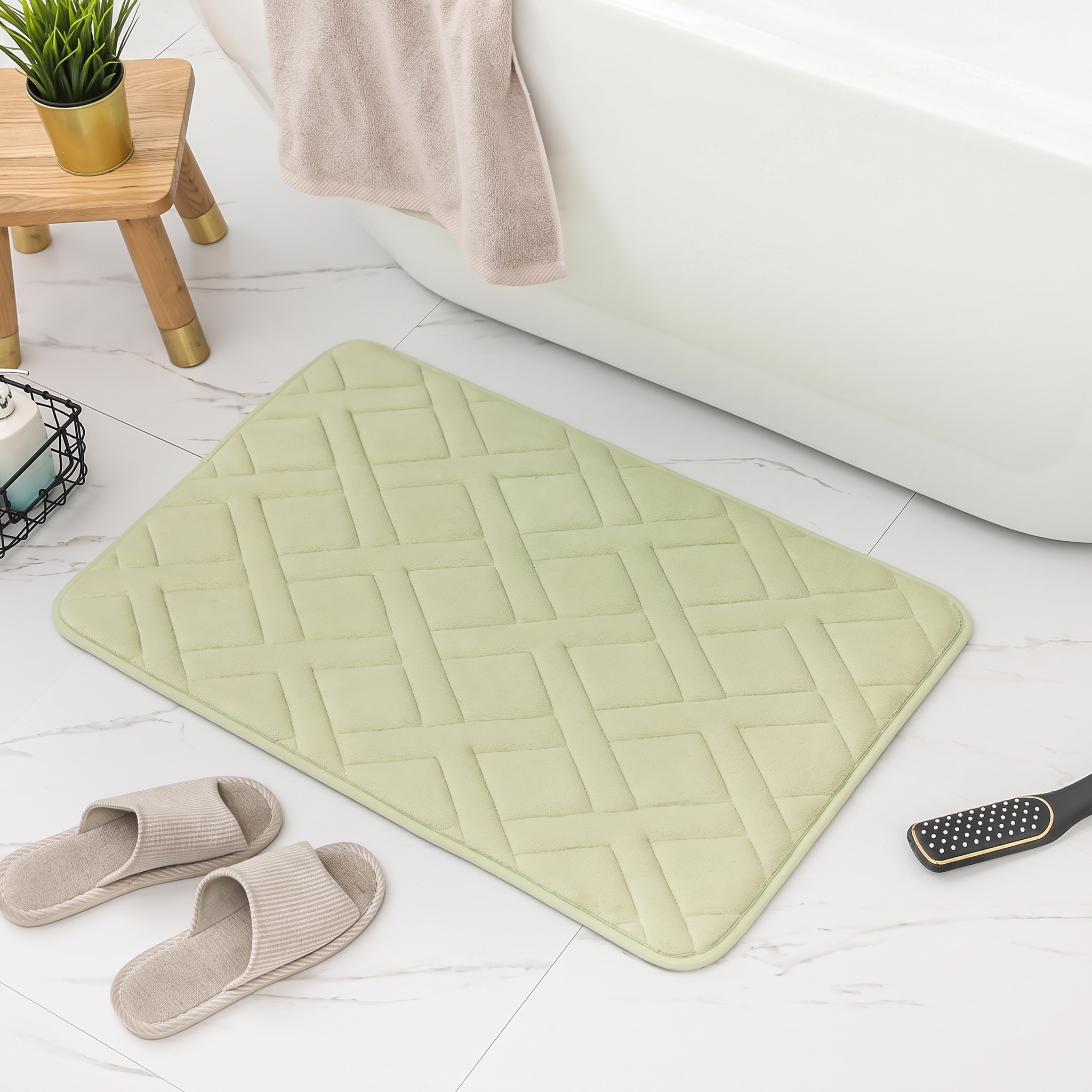 Light green bath mat on a bathroom floor with slippers and a plant in the background.