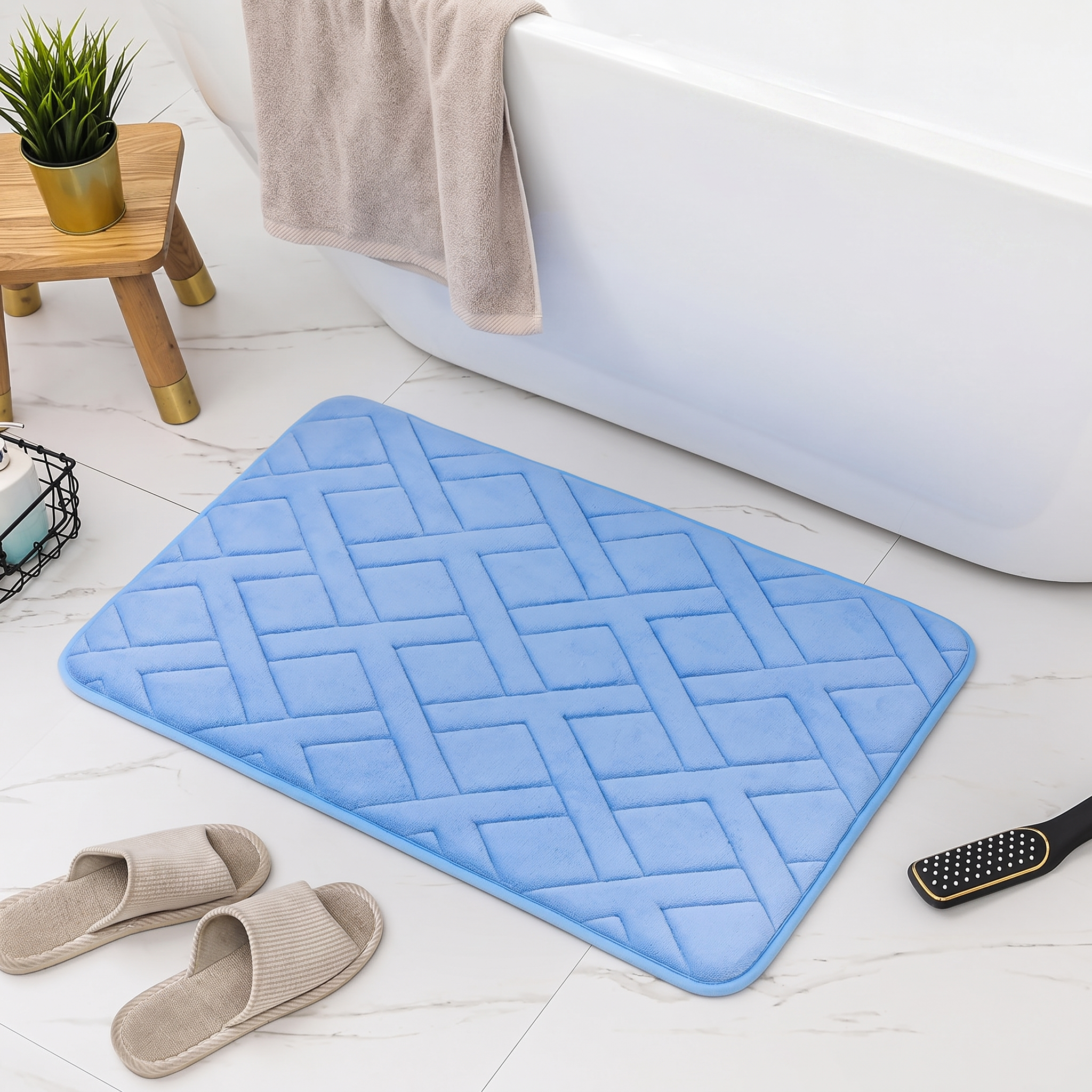 Blue bath mat with geometric pattern on a bathroom floor, next to a bathtub and slippers.