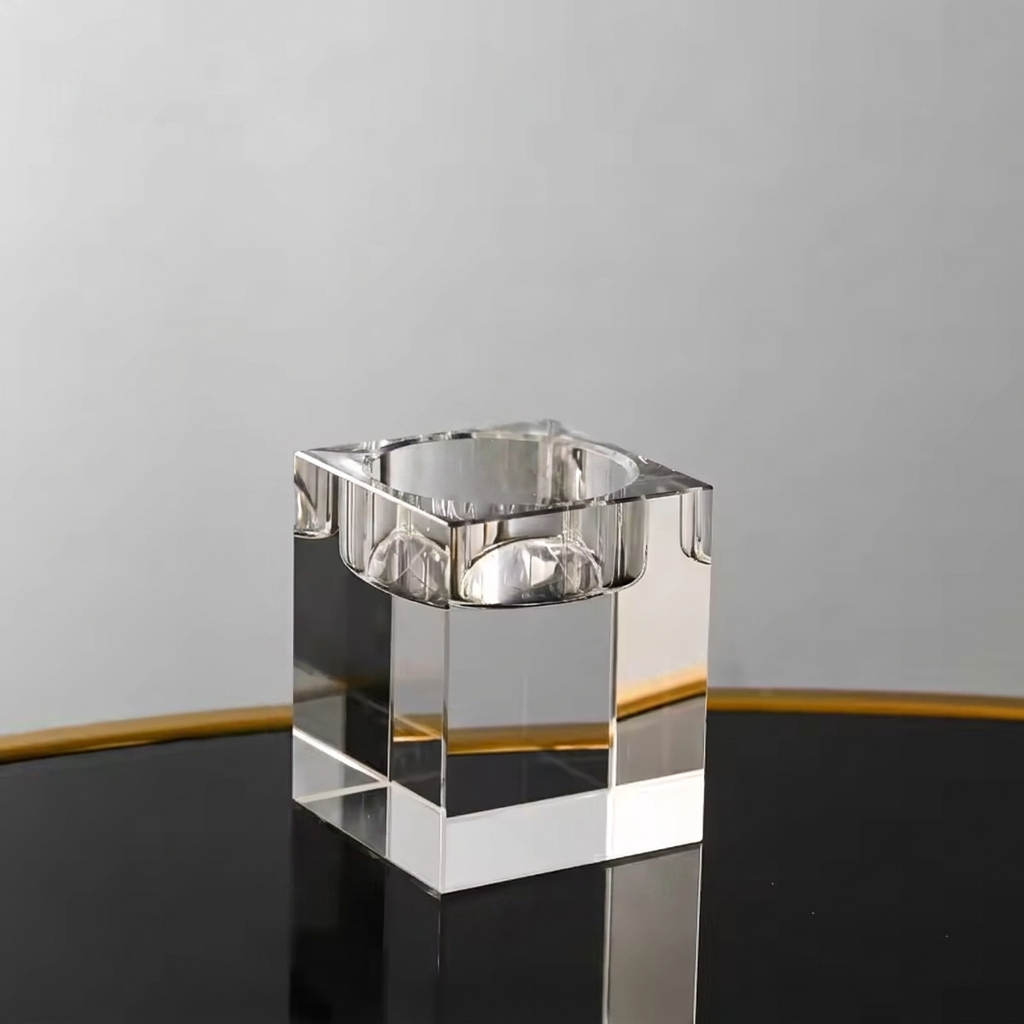 Clear glass candle holder on a reflective surface with a neutral background
