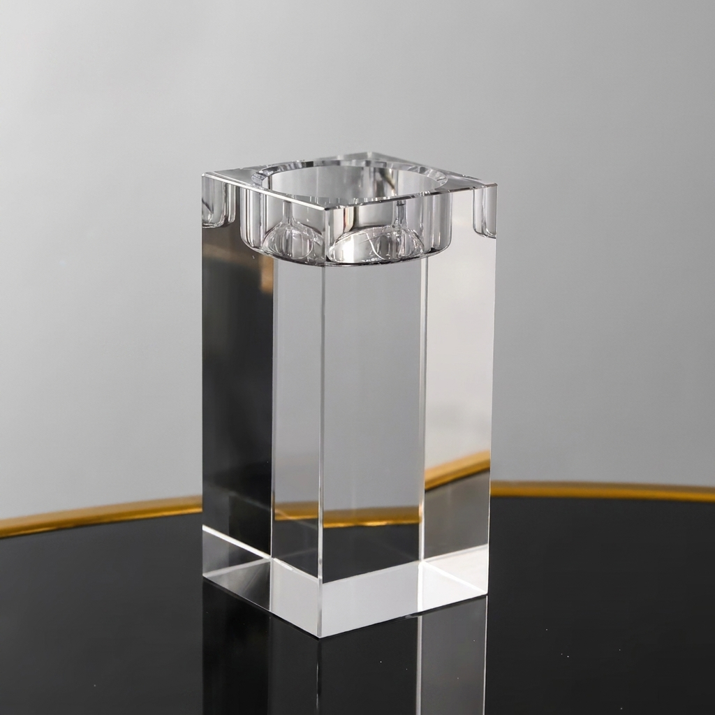 A clear rectangular glass or acrylic candle holder with a square top, shown on a reflective black surface against a light gray background.