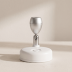A modern white and silver electronic device with a circular base and a metallic dome-shaped top, shown on a neutral beige background.