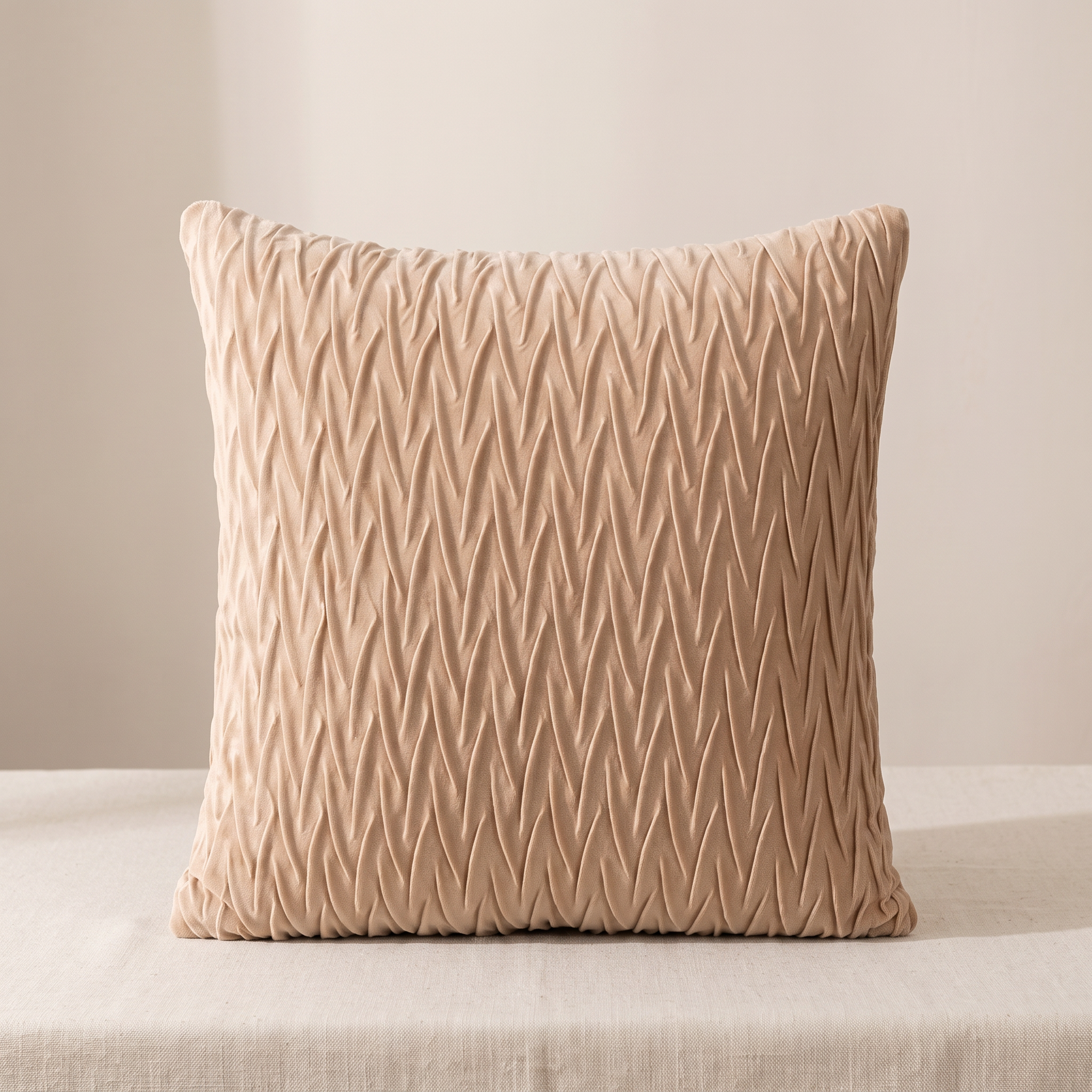 A square beige throw pillow with a textured chevron pattern, resting on a light beige fabric surface against a neutral beige background.