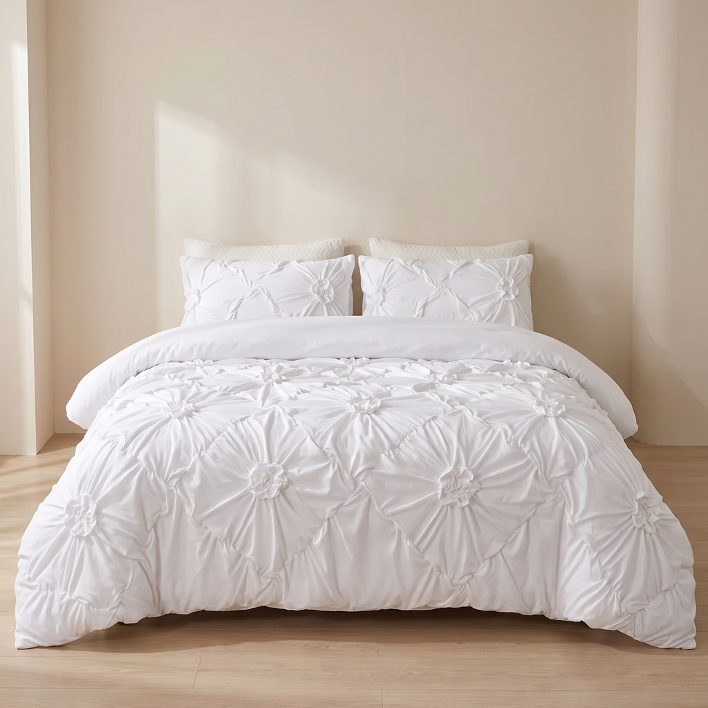 A white textured bedding set with a quilted floral pattern and matching pillowcases, styled on a bed in a minimalist beige bedroom.