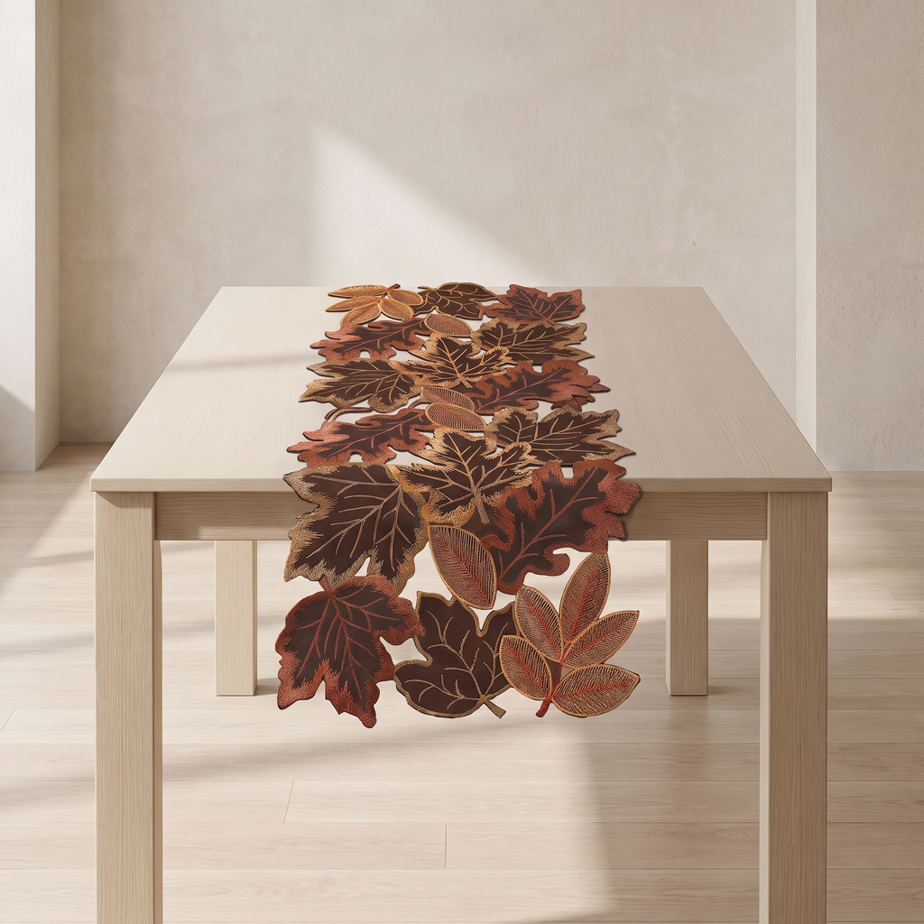 An autumn-themed table runner made of layered, realistic faux leaves in shades of brown, rust, and orange, displayed on a light wood dining table in a minimalist room.