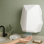 A white wall-mounted hand dryer with a geometric design, shown with a person's hand hovering under it in a bathroom setting.